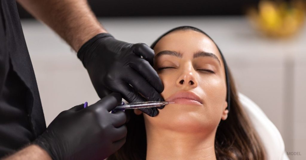 doctor injecting lip fillers into woman's lips (MODEL)